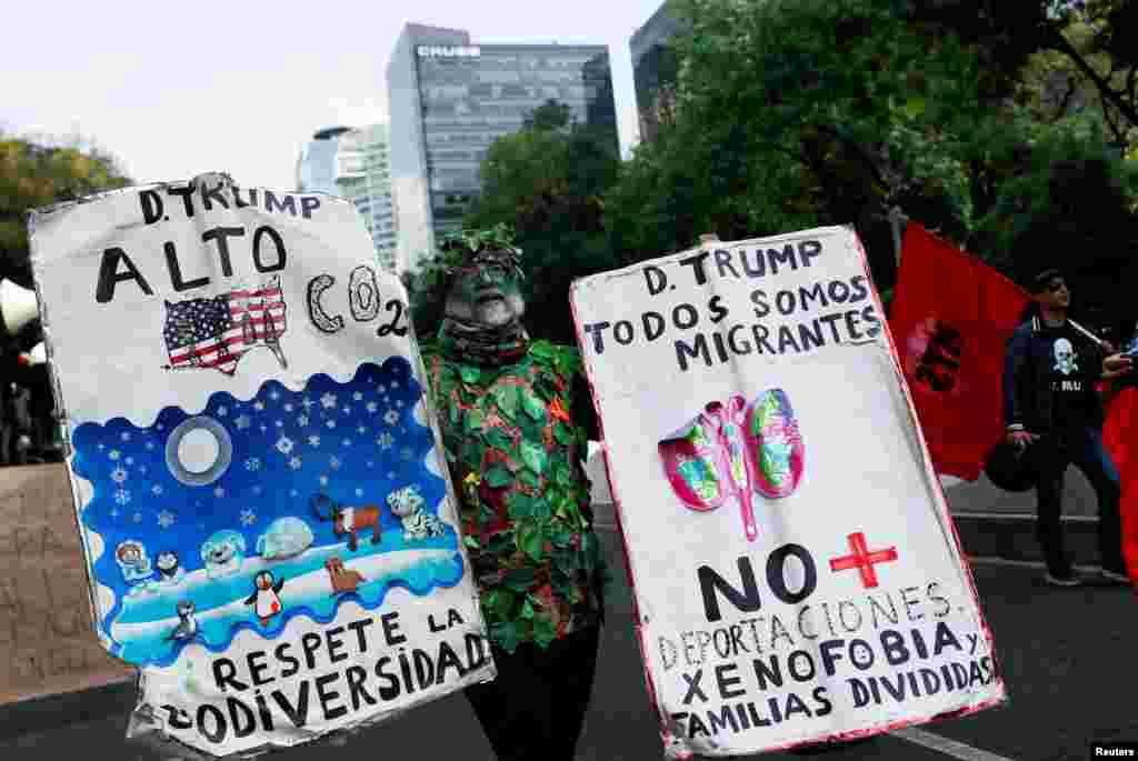 A demonstrator holds placards as he marches in a protest against U.S. President Donald Trump, near the U.S. Embassy in Mexico City, Mexico, Jan. 20, 2025.