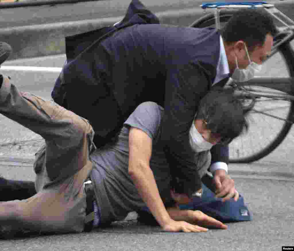 A man, believed to be a suspect shooting former Japanese Prime Minister Shinzo Abe, is held by police officers at Yamato Saidaiji Station in Nara, Nara Prefecture, July 8, 2022 in this photo taken by the Yomiuri Shimbun. 