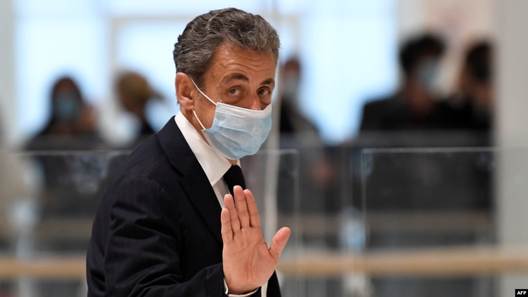 Former French president Nicolas Sarkozy waves as he leaves the court room during a break of his trial for attempted bribery of a judge, in Paris on November 23, 2020