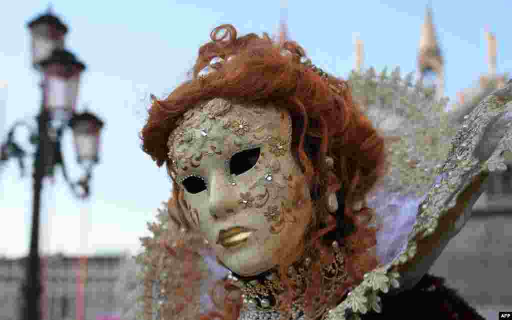 A masked reveler is een in Venice's Riva degli Schiavoni on the opening day of the Venice Carnival, Italy.