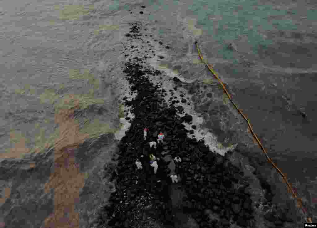 Workers clean the beach near Repsol's La Pampilla refinery after the recent oil spill that has caused an ecological disaster on the coast of Lima, in Ventanilla, Peru, Jan. 29, 2022.