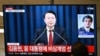 Um homem assiste ao discurso do Presidente da Coreia do Sul, Yoon Suk Yeol, durante um noticiário transmitido por uma televisão numa estação de comboios em Seul, a 3 de dezembro de 2024.