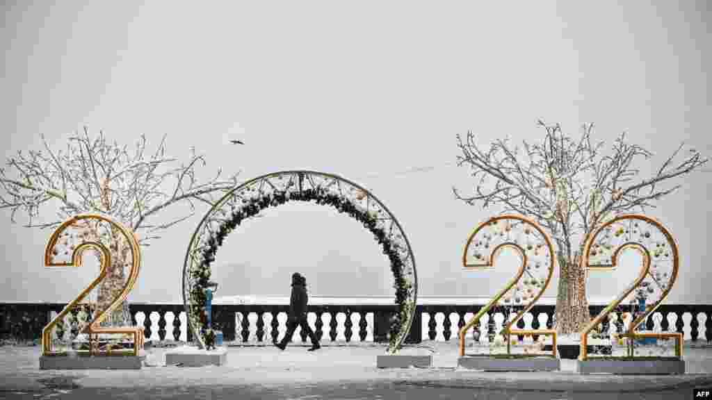 A man walks past large numbers for the upcoming year 2022, as part of Christmas and New Year decorations at Vorobyovy Hills observation point in Moscow.