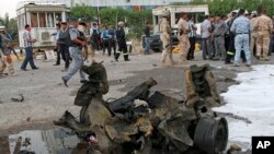 People and security forces inspect the scene of a car bomb attack in Basra, 340 miles (550 kilometers) southeast of Baghdad, Iraq, July 2, 2013. 