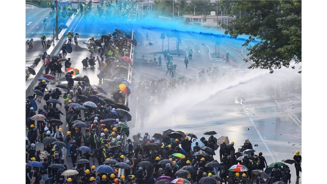 FILE - Pro-democracy protesters react as police fire water cannons outside the government headquarters in Hong Kong.