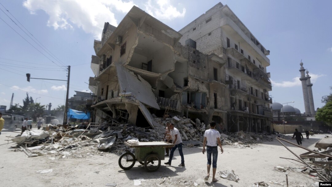 A man pushes a cart near damaged buildings in Aleppo's al-Saliheen district, May 2, 2015. 