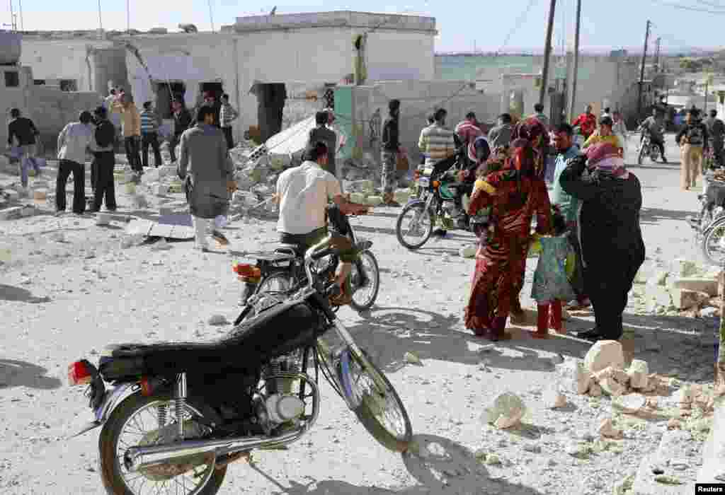 People inspect a site hit by what activists said were barrel bombs dropped by forces loyal to President Bashar al-Assad, in al-Letmana village, Hama province, May 1, 2014. 