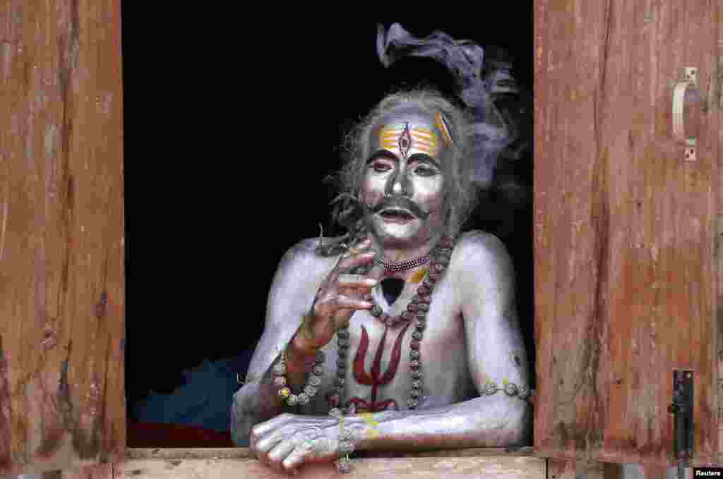 A devotee smokes as he waits to perform during the annual Hindu festival of Gajan on the outskirts of Agartala, India, April 13, 2019.