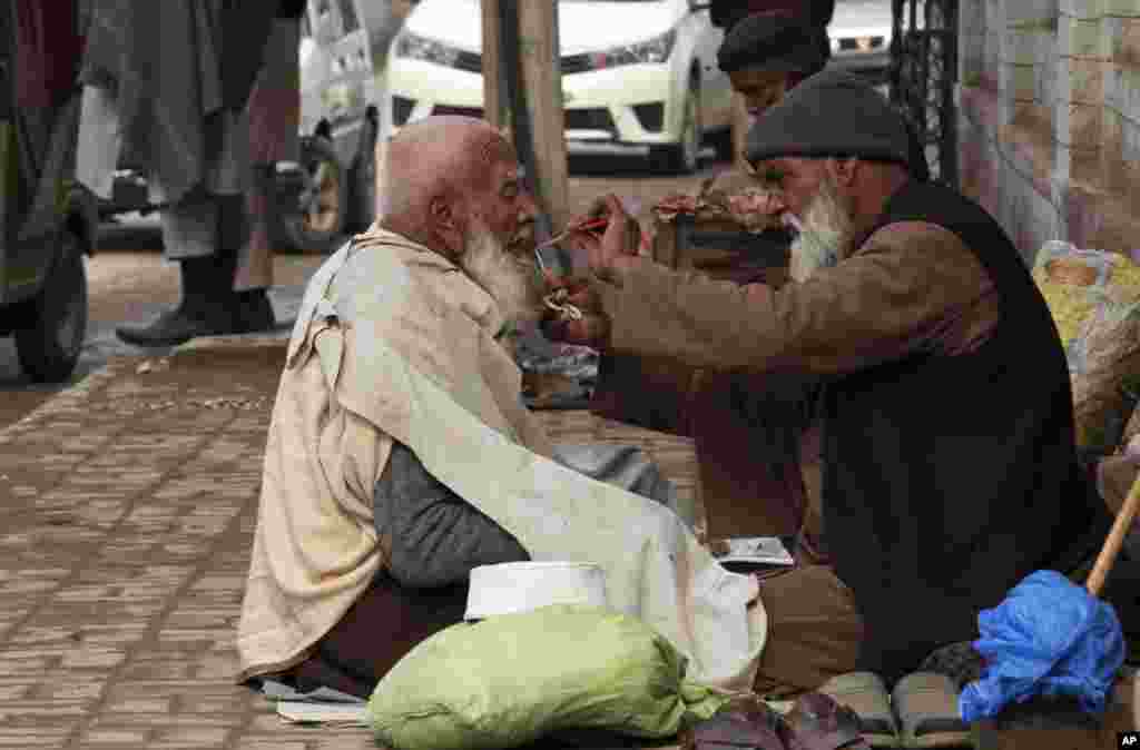 A street barber trims a costumer's beard in Peshawar, Pakistan. 