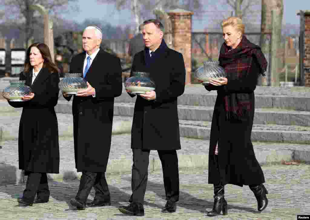 U.S. Vice President Mike Pence with his wife Karen and Poland's President Andrzej Duda with first lady Agata Kornhauser-Duda carry candles at the Monument to the Victims at the former Nazi German concentration and extermination camp Auschwitz II-Birkenau, near Oswiecim, Poland.