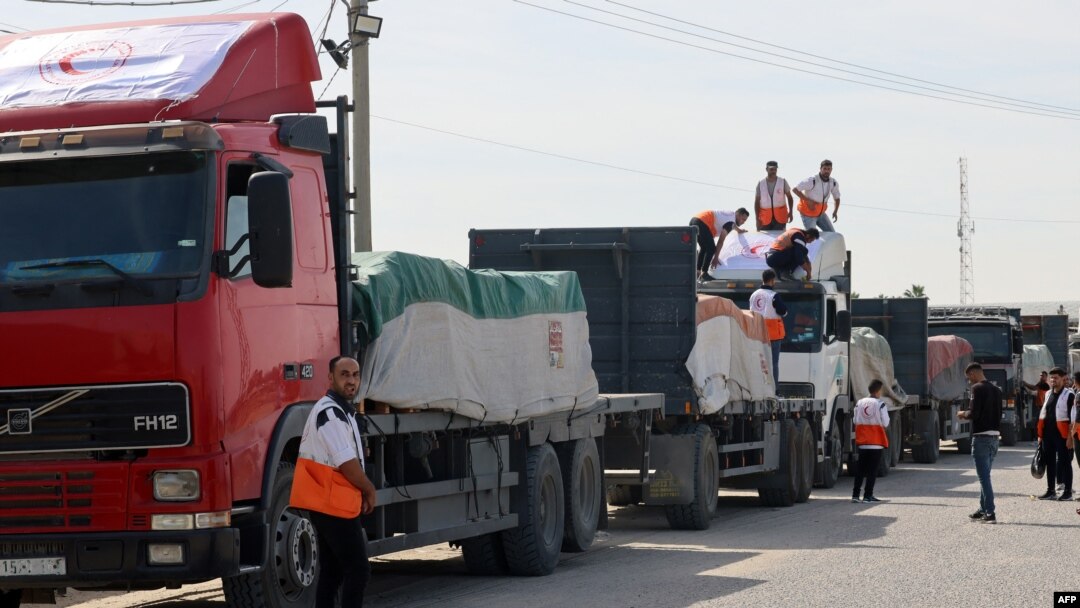 Trabalhadores do Crescente Vermelho Palestino descarregam camiões que transportam ajuda humanitária depois de entrarem na Faixa de Gaza vindos do Egipto através da passagem de fronteira de Rafah, 21 de outubro de 2023.
