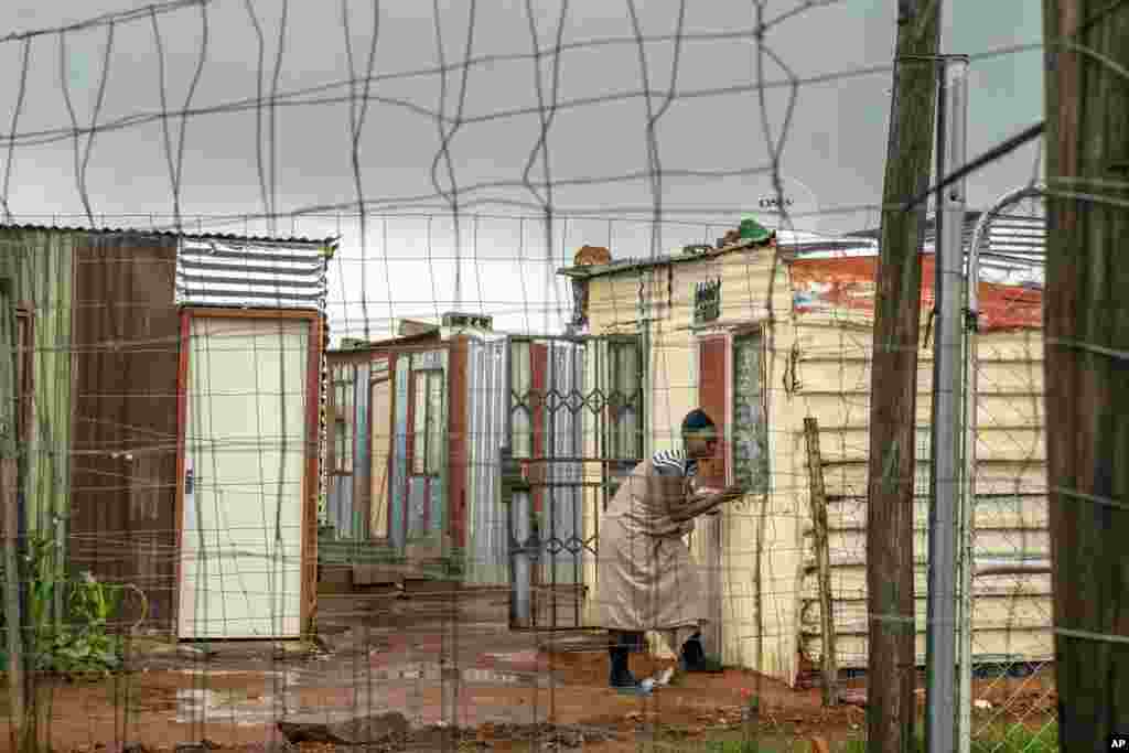 A woman living in the Vlakfontein informal settlement outside Johannesburg, South Africa, shuts her window during a rainstorm.