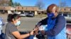 Clint Mitchell, the principal of Mount Vernon Woods Elementary School in Alexandria, Virginia, hands a turkey to a woman who stopped by to pick up food for a Thanksgiving meal. (Deborah Block/VOA)