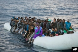 FILE - Migrants and refugees wait to be helped by members of the NGO Proactiva Open Arms, as they crowd aboard a rubber boat sailing out of control in the Mediterranean Sea about 21 miles north of Sabratha, Libya, Feb. 3, 2017.