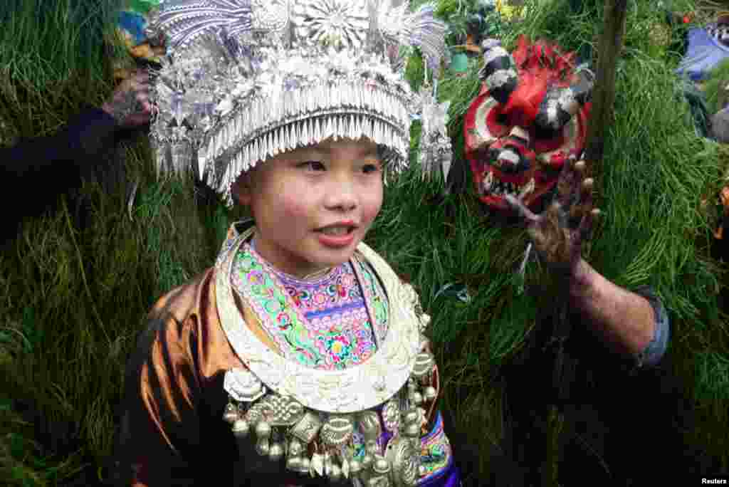 An ethnic Miao woman poses with Miao men dressed as "Manghao" during an event to celebrate the Manghao Festival at Rongshui Miao Autonomous County, in Liuzhou, Guangxi Zhuang Autonomous Region, China, Feb. 13, 2019.