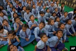 School children look at a drone camera during the inauguration ceremony of a water filtration tower at their school in Nai Basti Village, near New Delhi, India, March 22, 2017.