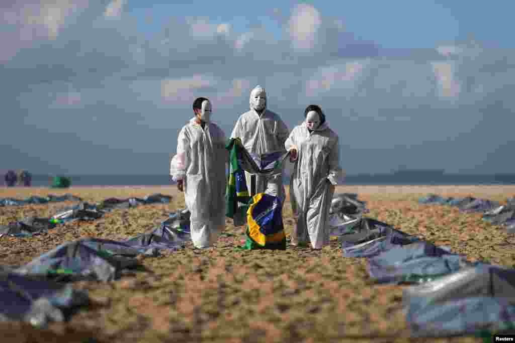 Activists from NGO Rio de Paz carry a Brazilian flag as they display hundreds of plastic bags, representing dead bodies, during a protest against Jair Bolsonaro's COVID-19 policies, in Copacabana beach, in Rio de Janeiro, Brazil.