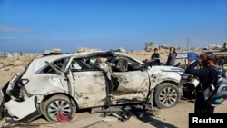 Palestinianos inspeccionam o veículo em que se encontravam os empregados da World Central Kitchen (WCK) mortos num ataque israelita, em Khan Younis