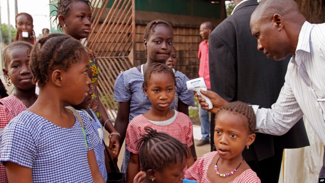 FILE - A health care worker, right, takes the temperatures of schoolchildren for signs of the Ebola virus before they enter their school in Conakry, Guinea, Jan. 19, 2015.