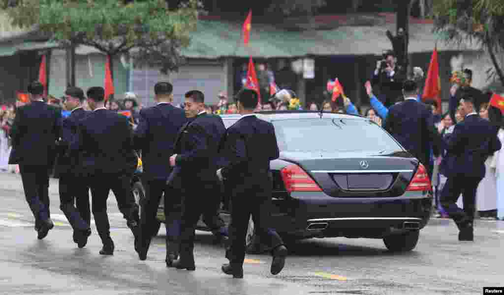 North Korean bodyguards run along a limousine transporting North Korea's leader Kim Jong Un upon his arrival at the border town with China in Dong Dang, Vietnam.
