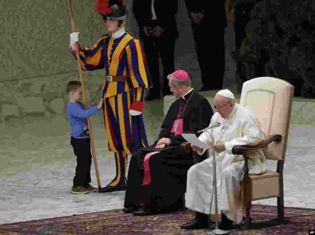 A child plays with a Swiss guard in the Paul VI Hall at the Vatican.