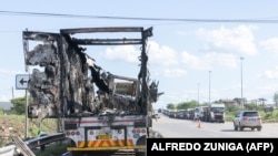 Visão geral de um camião queimado enquanto outros camiões fazem fila para tentar chegar ao posto de fronteira de Ressano Garcia, entre Moçambique e África do Sul, em 13 de novembro de 2024