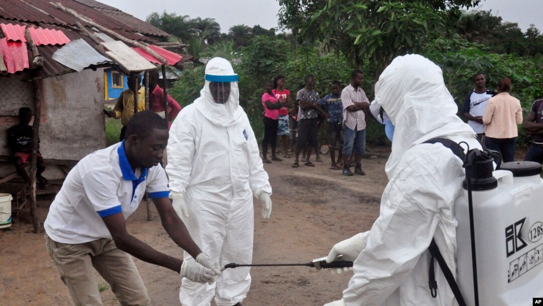 FILE - Health workers wash their hands after taking a blood specimen from a child to test for the Ebola virus in a area were a 17-year old boy died from the virus on the outskirts of Monrovia, Liberia. 