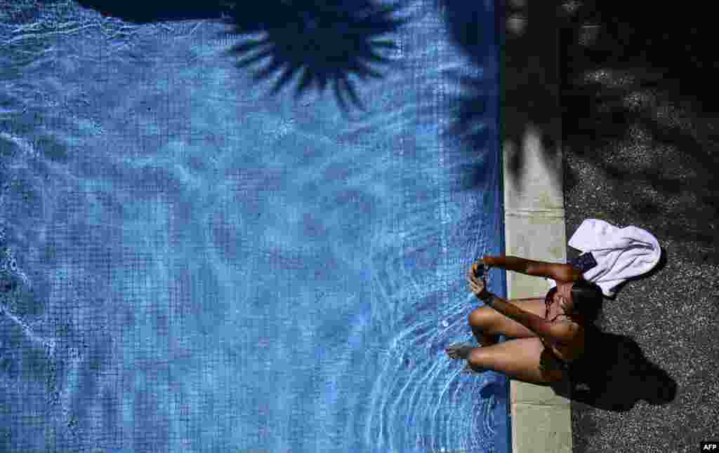 A woman takes a selfie in the pool in a Caracas hotel, the government of Venezuela recalled public workers workers after a week-long unprecedented nationwide blackout.