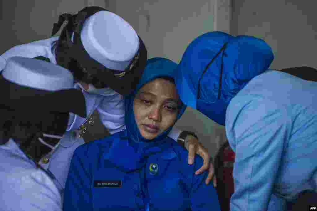 Military personnel console a sailor's wife during a remembrance ceremony for the crew of the Indonesian navy submarine KRI Nanggala that sank on April 21 during a training exercise, on the deck of the hospital ship KRI Dr. Soeharso off the coast of Bali.