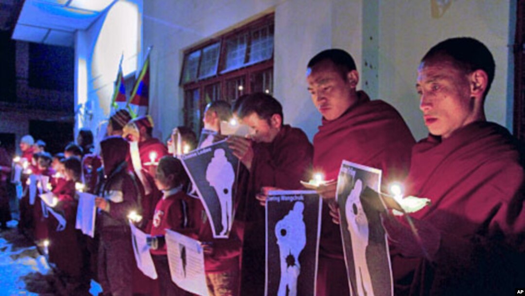 January 25, 2012, file photo shows Tibetan Buddhist monks holding pictures of Tibetans they claim were allegedly shot by Chinese security forces earlier this week, during a candlelight vigil in Dharamsala, India