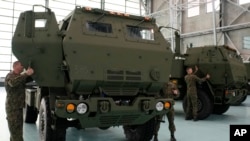 ARCHIVO - Soldados polacos observan un vehículo que transporta uno de los lanzacohetes HIMARS de fabricación estadounidense, en una base aérea en Varsovia, Polonia, el lunes 15 de mayo de 2023. 
