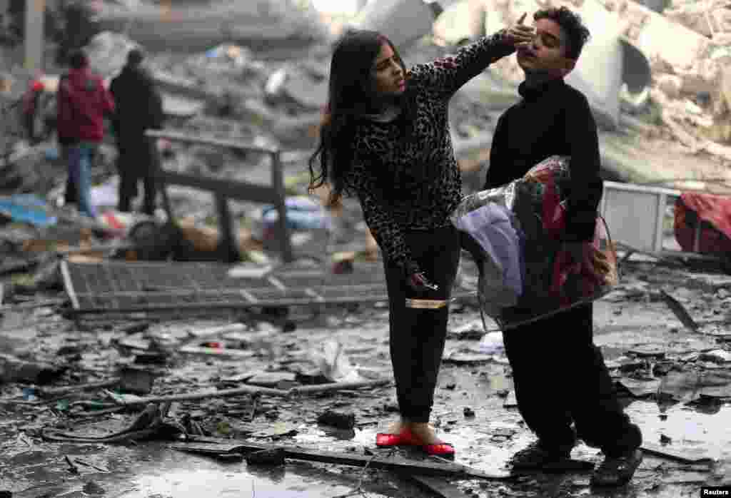 A Palestinian girl cleans her brother's face outside their destroyed house after an Israeli missile targeted a nearby Hamas site, in Gaza City, in the Gaza Strip.