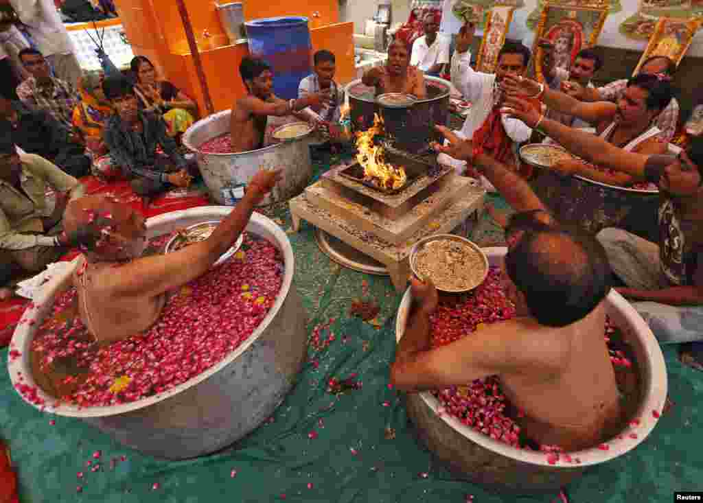 Hindu priests sit in cauldrons of water and rose petals as they perform the "Parjanya Varun Yagam", a special prayer for rain, in the western Indian city of Ahmedabad.