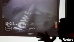 Head of the National Search and Rescue Agency Fransiskus Bambang Soelistyo is seen with an image believed to be of the fuselage of AirAsia Flight QZ8501, taken by an underwater ROV provided by the Singaporean Navy, during a news conference in Jakarta, Jan. 14, 2015.