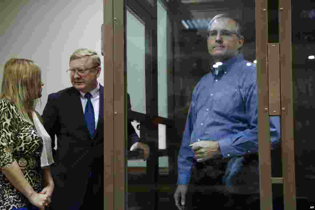 Paul Whelan, a former U.S. Marine, who was arrested in Moscow at the end of last year, right, looks through a cage's glass as his lawyers talk to each other in a court room in Moscow, Russia. The lawyer for Paul Whelan who is being held in Moscow on suspicion of spying, said that classified Russian materials were found with him when he was arrested.