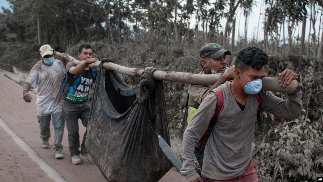 Residentes llevan un cuerpo recuperado cerca del Volcán de Fuego en Escuintla, Guatemala, el lunes, 4 de junio de 2018.
