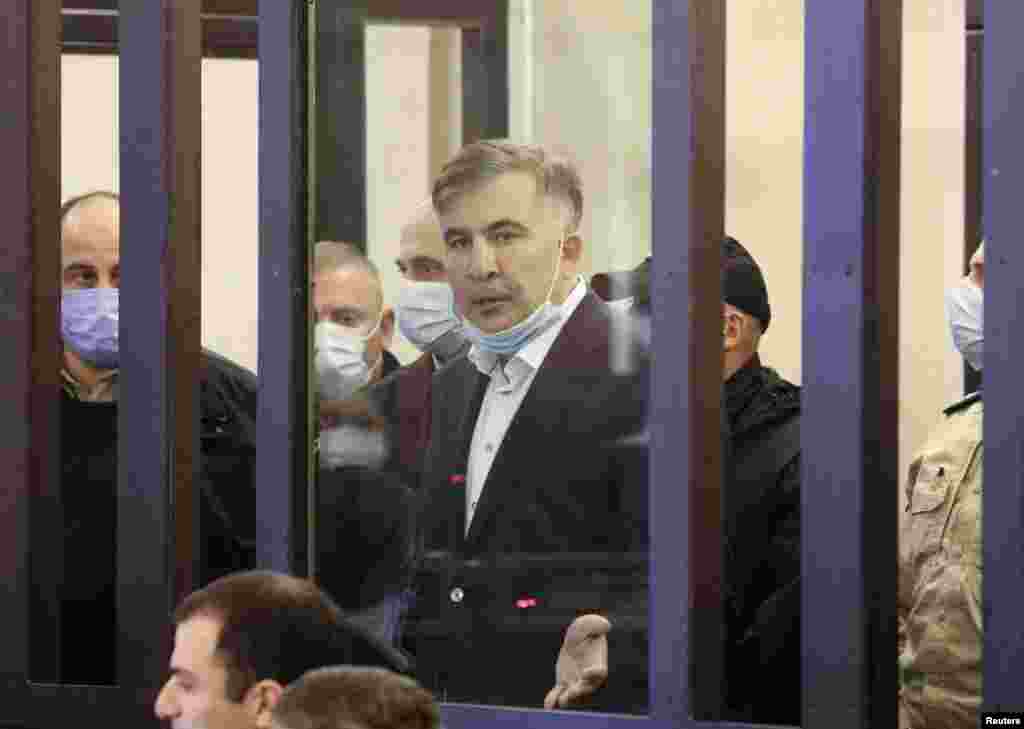 Georgian former President Mikheil Saakashvili, who was convicted in absentia of abuse of power during his presidency and arrested upon his return from exile, reacts inside a defendant's dock during a court hearing in Tbilisi.