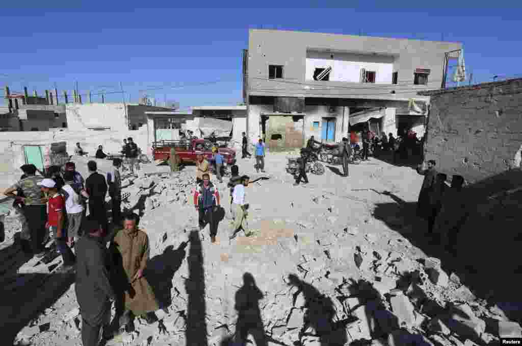 People inspect a site hit by what activists said were barrel bombs dropped by forces loyal to President Bashar al-Assad, in al-Letmana village, Hama province, May 1, 2014. 