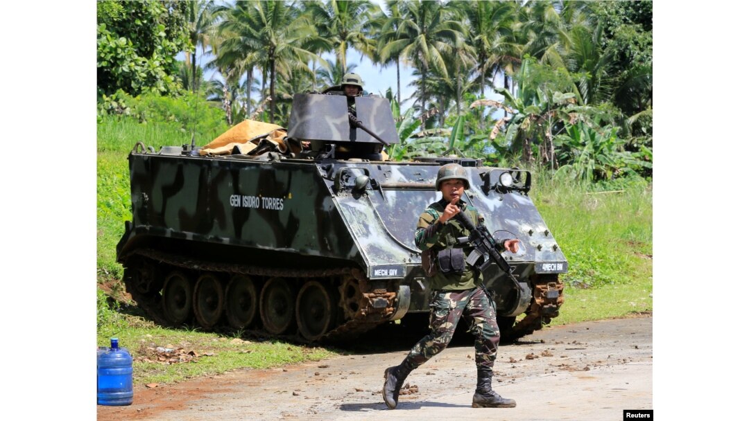 A government troop gestures as he passes an armoured personnel carrier posted along a main highway of Pantar town, Lanao Del Norte, after residents start to evacuate their hometown of Marawi city, southern Philippines, May 24, 2017.