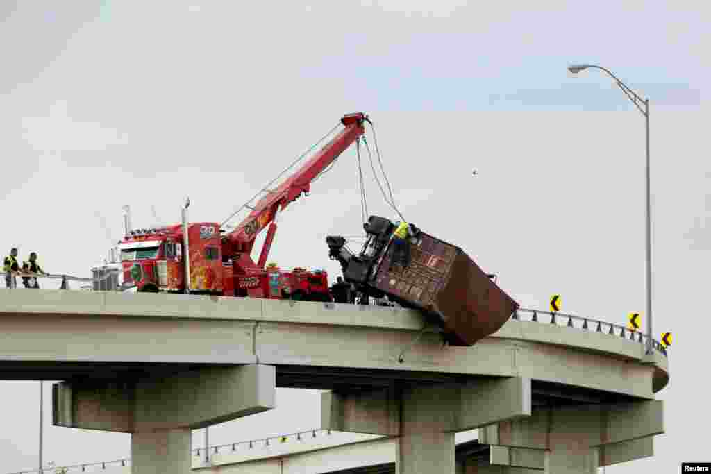 Workers assist as a trailer hangs from the U.S. 54 highway on the U.S side of El Paso Texas, as seen from Ciudad Juarez, Mexico, July 3, 2017.