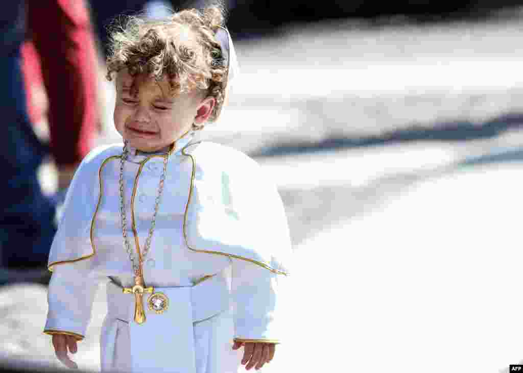 A child dressed as a Pope cries during the weekly Angelus prayer at St. Peter's square in the Vatican.