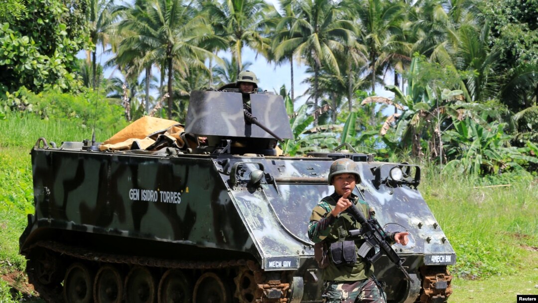 A government troop gestures as he passes an armoured personnel carrier posted along a main highway of Pantar town, Lanao Del Norte, after residents start to evacuate their hometown of Marawi city, southern Philippines, May 24, 2017.