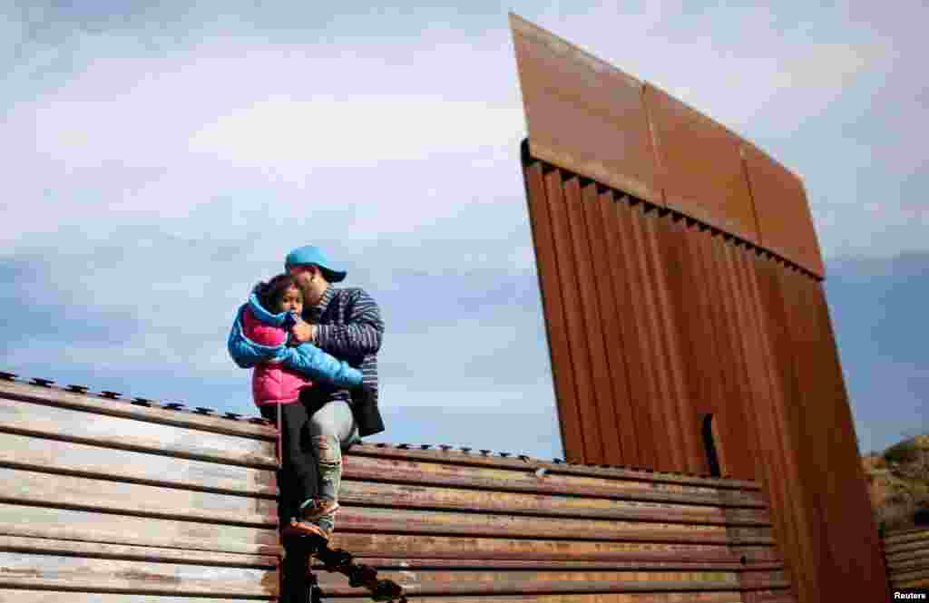 Migrants from Honduras, part of a caravan of thousands from Central America trying to reach the United States, jump onto a border fence to cross illegally from Mexico to the U.S., in Tijuana, Mexico, Dec. 12, 2018.