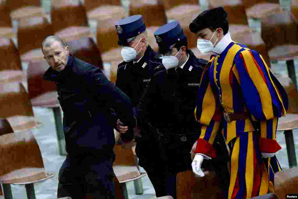 Members of the gendarmerie and a member of the Pontifical Swiss Guard escort out of the Vatican a man who interrupted Pope Francis' weekly general audience.