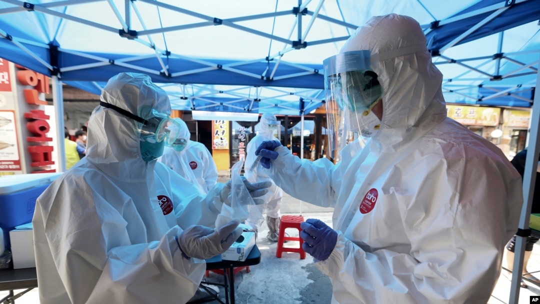 A health official wearing protective gears puts a sample of a person into a plastic bag during the COVID-19 testing at a makeshift clinic in Seoul, South Korea, Friday, June 5, 2020. (AP Photo/Ahn Young-joon)