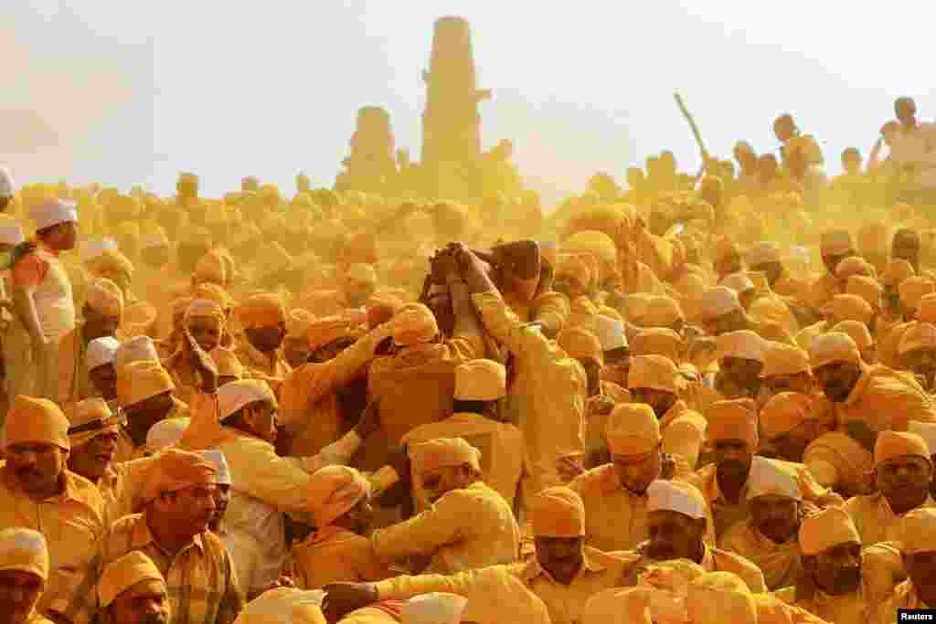 Devotees throw turmeric powder as an offering to the shepherd god Khandoba as others carry a palanquin during 'Somvati Amavasya' at a temple in Jejuri, India, Feb. 4, 2019.