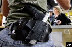 FILE - Kayla Brown, left, wears her gun on her hip while working at the Spring Guns and Ammo store in Spring, Texas, JAN. 4, 2016.