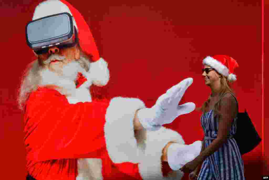 A woman walks past a giant Santa Claus poster at Jumeirah Beach Residence in Dubai, United Arab Emirates.