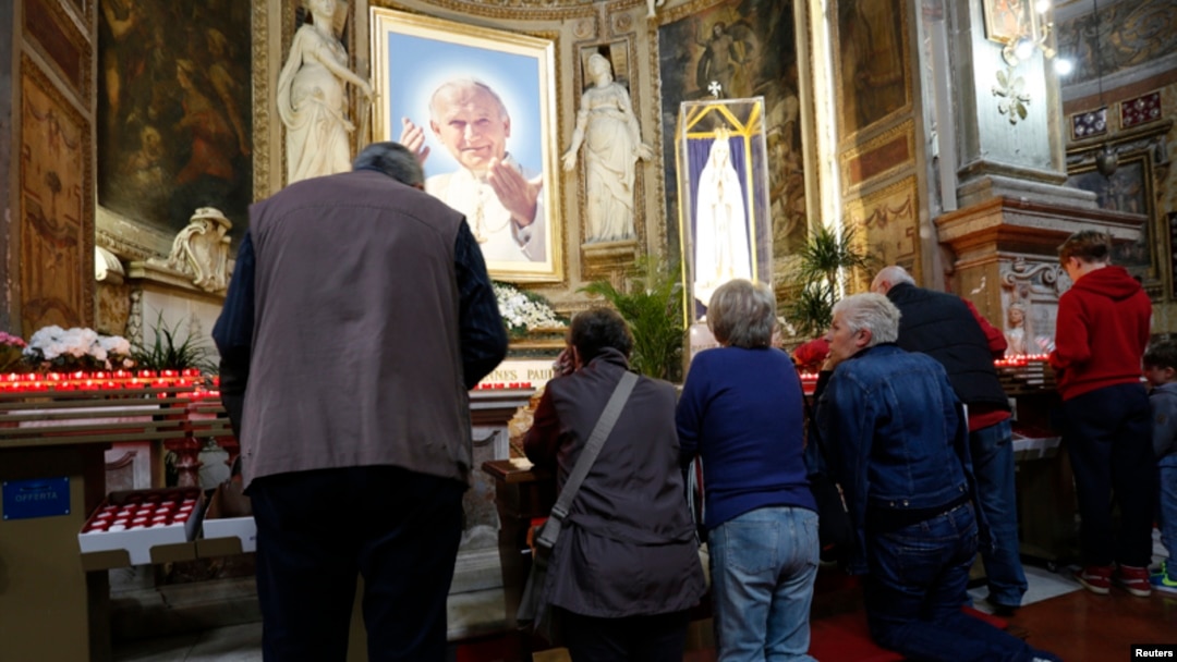 Católicos oran en una iglesia en Roma frente a una imagen del papa Juan Pablo II.