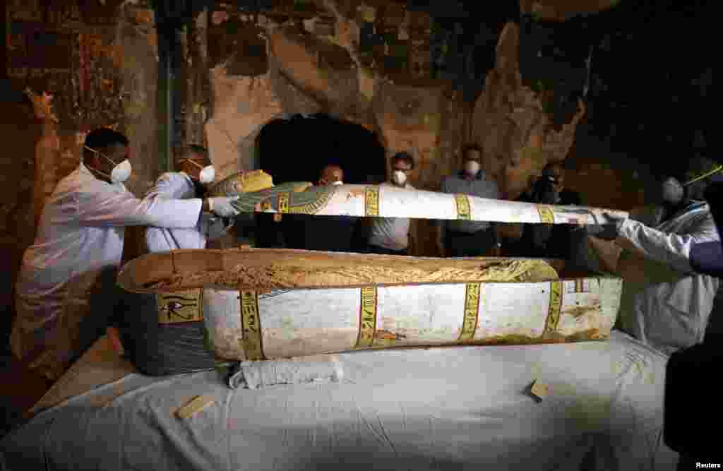 Archaeologists remove the cover of an intact sarcophagus inside the tomb TT33 in Luxor, Egypt, Nov. 24, 2018.